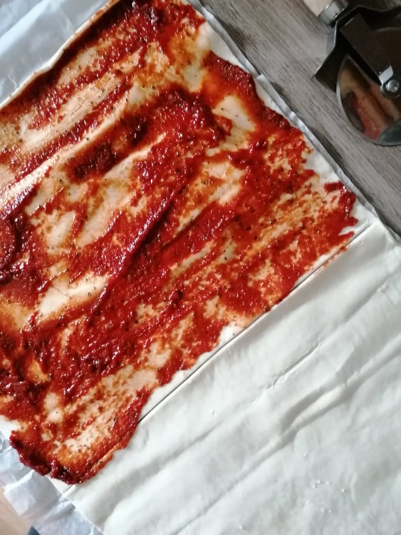 Krok pierwszy. Ciasto francuskie posmarowane sosem pomidorowym z ziołami